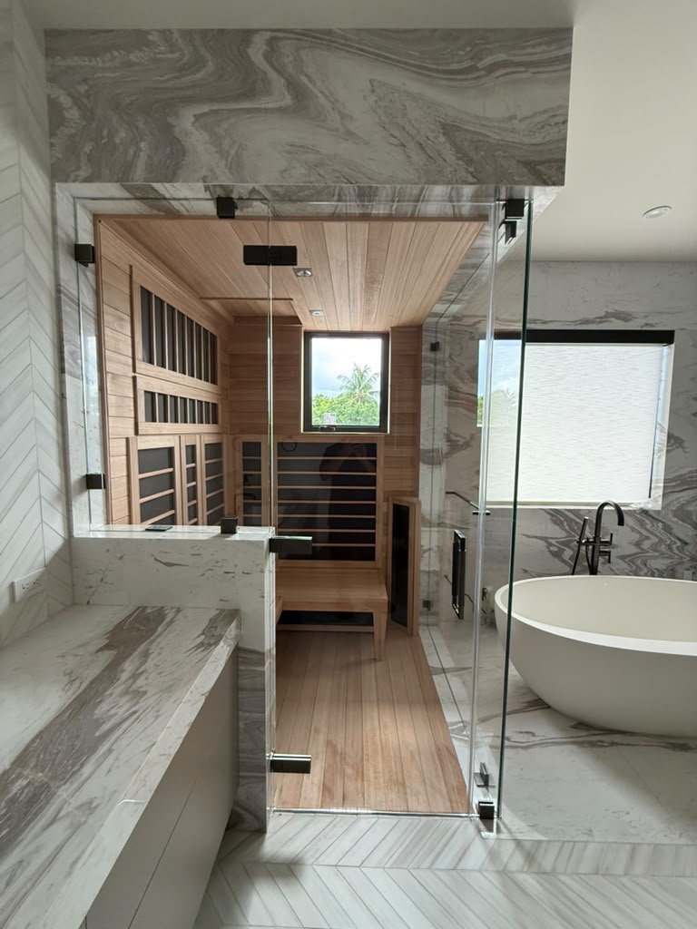Finished glass sauna enclosure with marble finishes and a freestanding tub